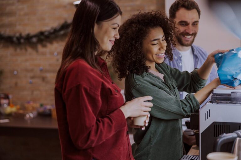 Des employés se servent un café autour d’une machine à café dans la salle de pause de l’entreprise.